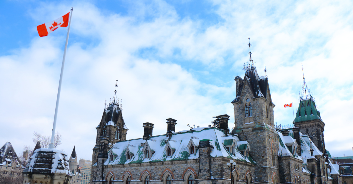 Canadian parliament building with snow on the roof and a blue and cloudy sky