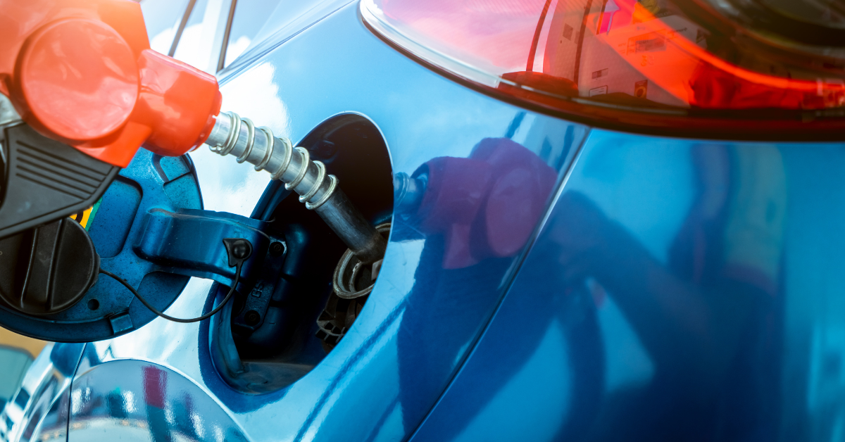 Red gas pump handle in a blue car's gas fuel tank