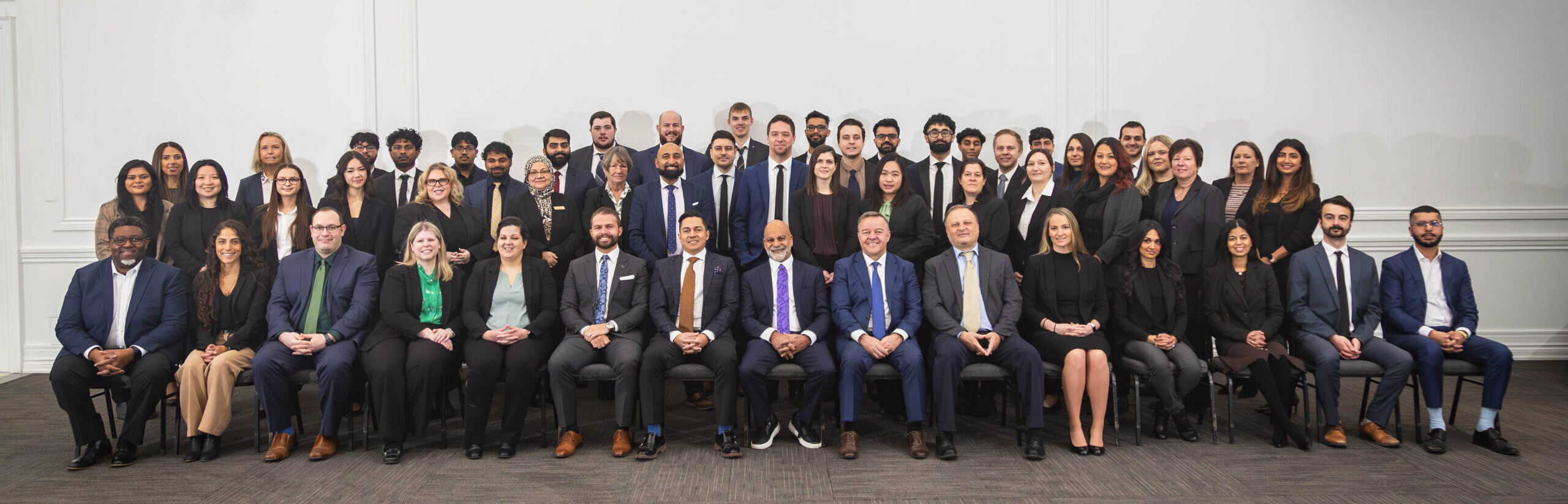 Team picture with all members of Bateman MacKay in business formal wear. First row, including Partners sitting down with two rows of standing